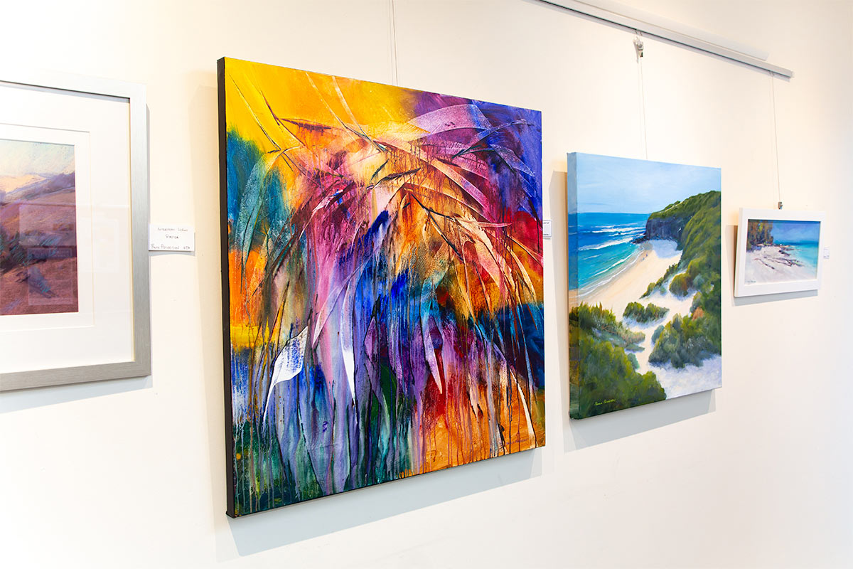 A group of paintings by Paula Petersen hanging on a gallery wall