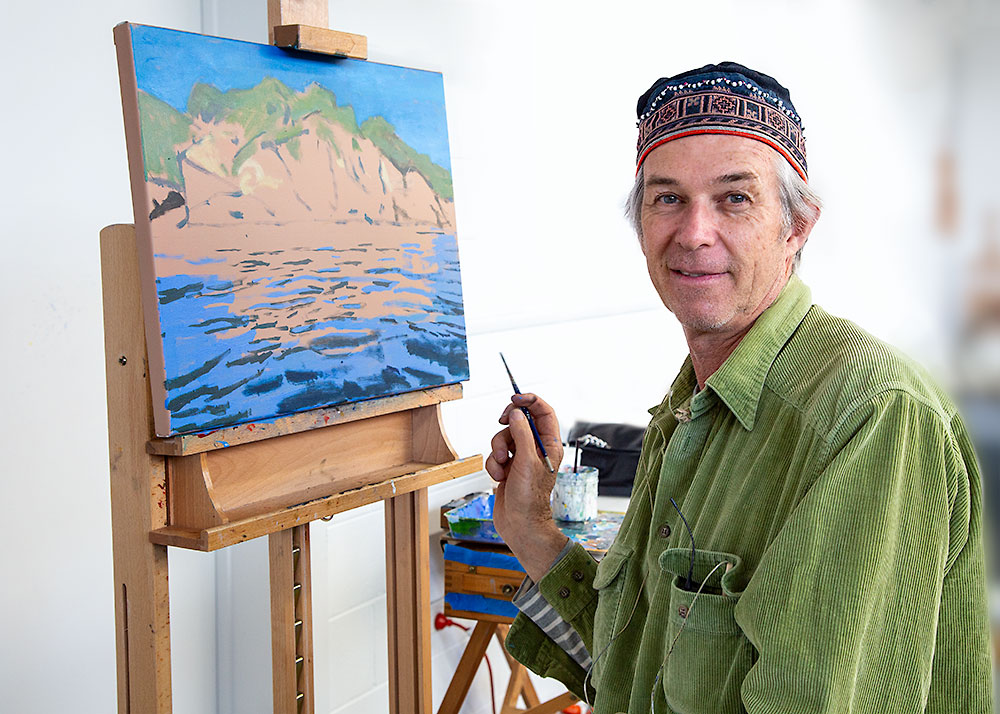Rick Matear's acrylic painting demonstration of a sunny seascape with orange-yellow cliffs and bright blue rippled water.