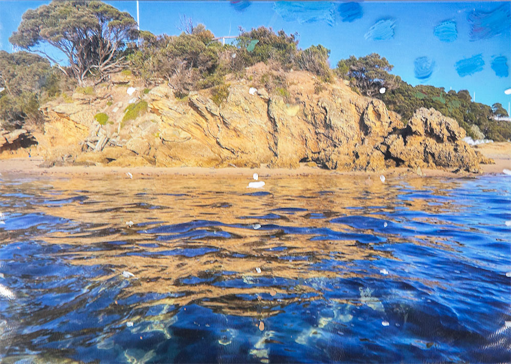 Reference photo for Rick Matear's acrylic painting demonstration of a sunny seascape with orange-yellow cliffs and bright blue rippled water.
