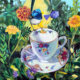 GardenTea - oil painting by Jenni Guilfloyle of a fine china floral teacup with a blue wren perched on it and flowers and foliage in the background.