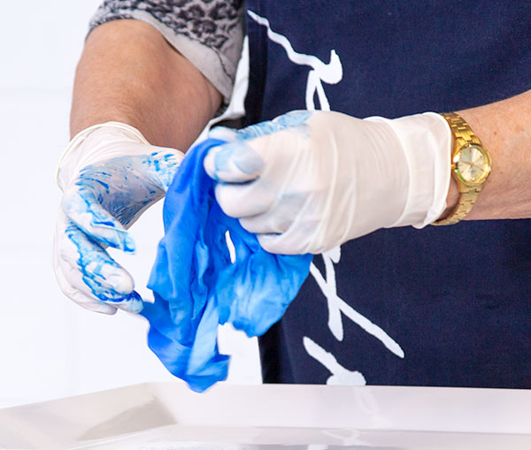 One Colour Dyeing - person working blue dye through a piece of fabric by hand.