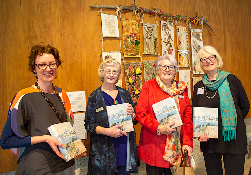 On Bunurong Country - book launch. L-R author JaneEckett, PAS past President Ruth Quinn, PAS past President Margot O'Neil and author Hughes. Wall hanging with textile art in the background - created by the PAS Textile Group.