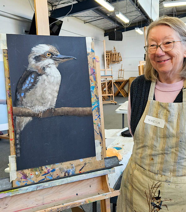 Angela Russo Pan Pastel Workshop - Sheila- woman holding pastel painting of a kookaburra.